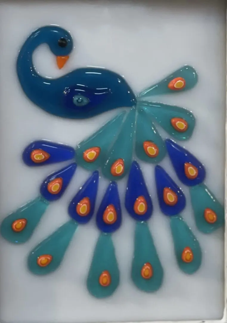 A glass peacock with blue and orange feathers.