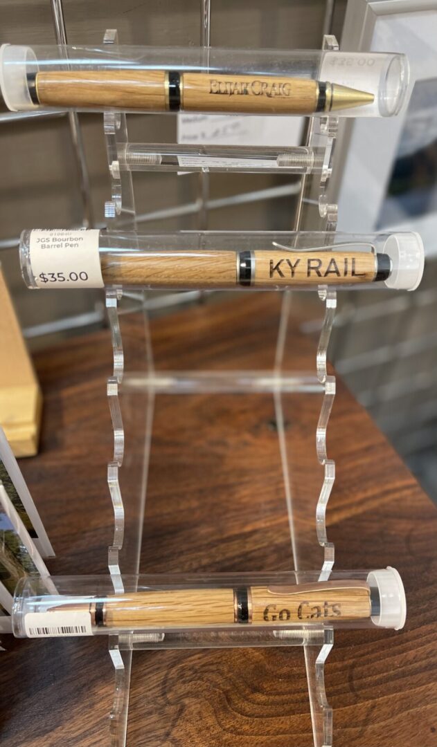 Three wooden pens on a display stand.