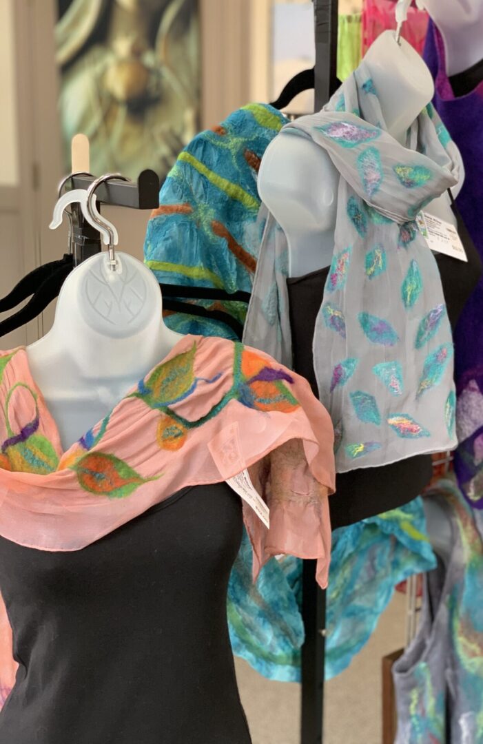 A display of colorful scarves on mannequins.