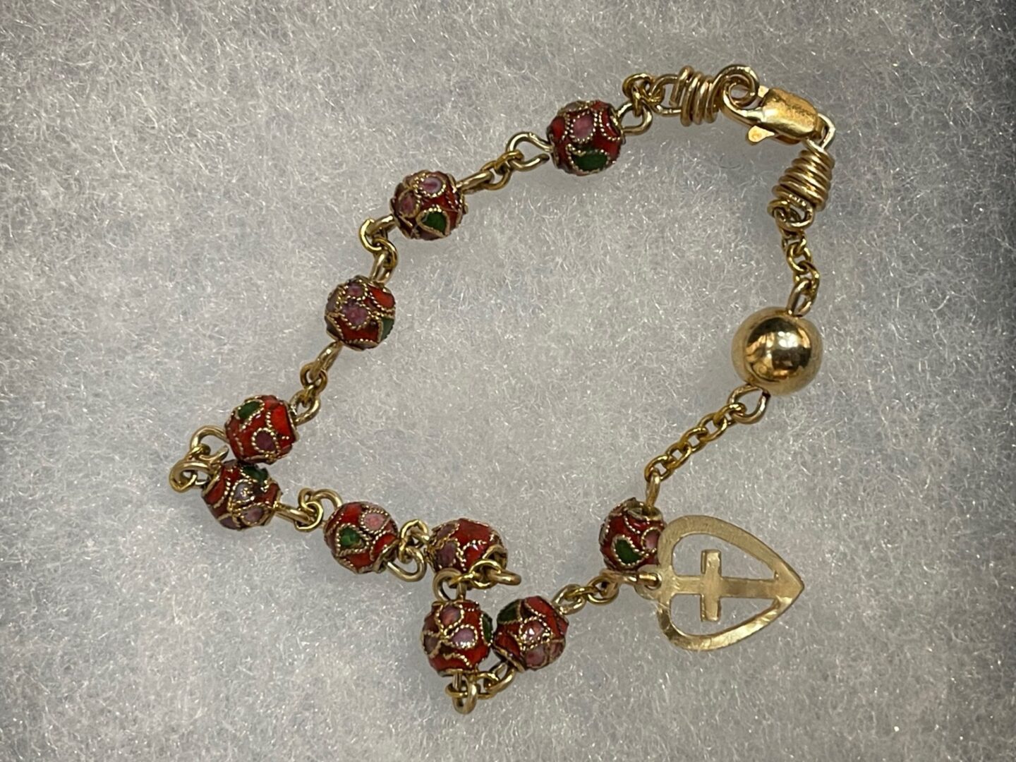 A gold plated bracelet with red and green beads.
