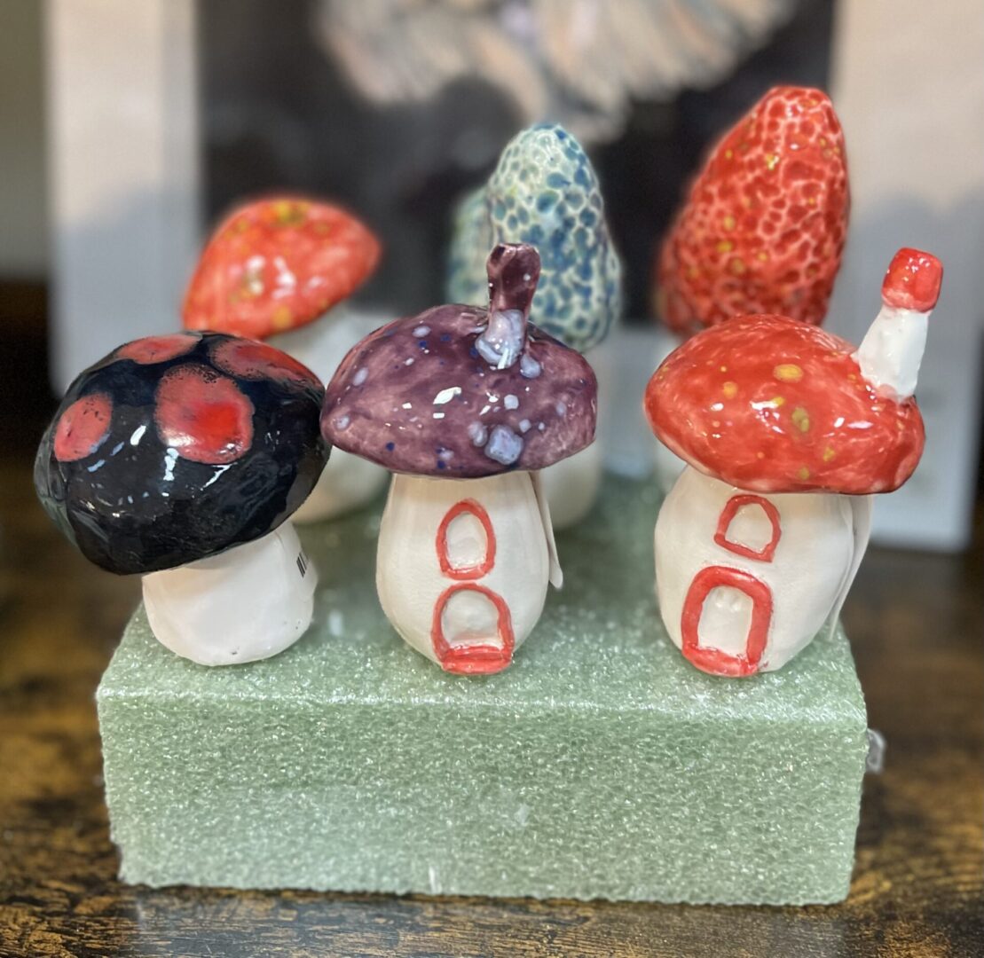 A group of ceramic mushrooms on top of a piece of wood.
