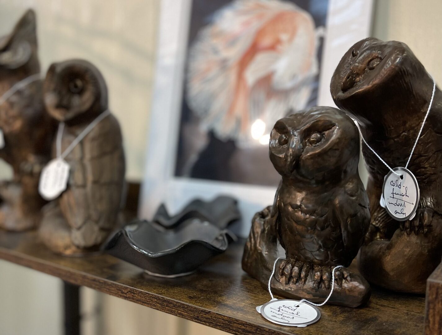 Three owl statues on a shelf.