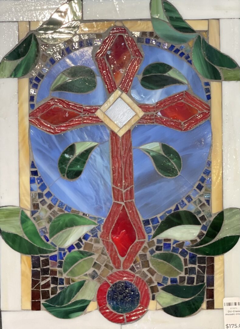A stained glass panel with a cross and leaves.