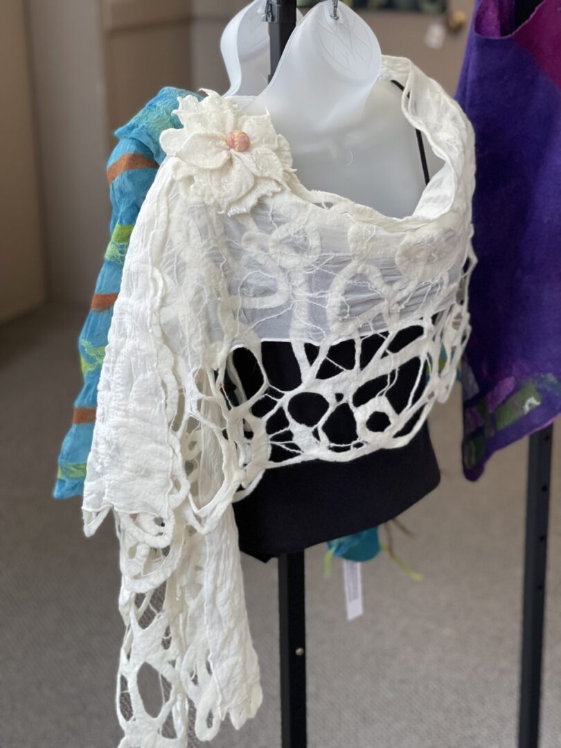 A white shawl hanging on a stand.