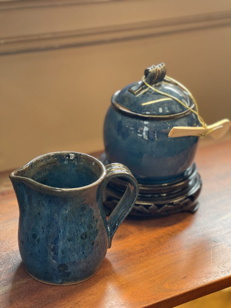 A blue jug and mug sit on a wooden table.