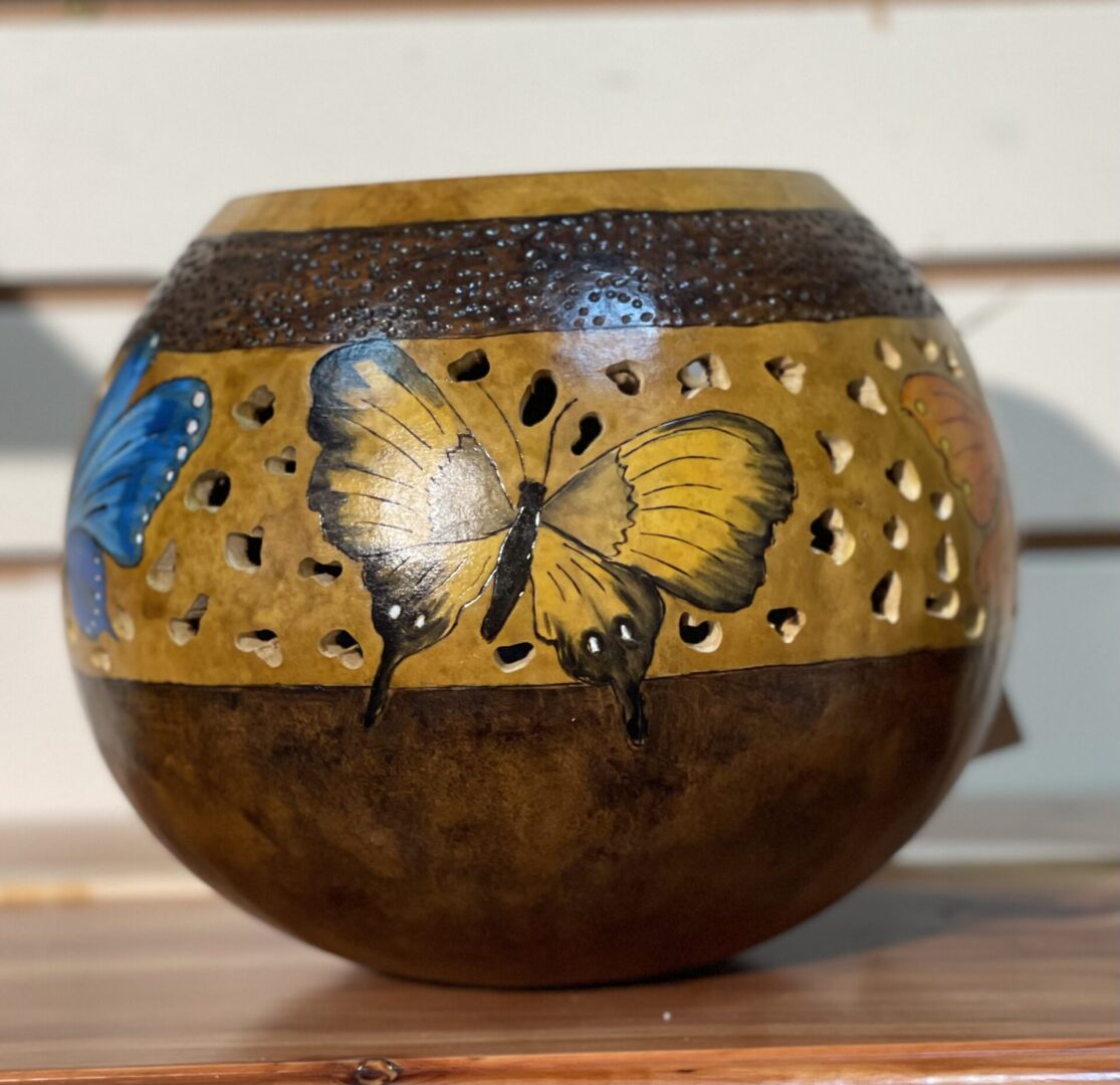 A wooden bowl with butterflies painted on it.
