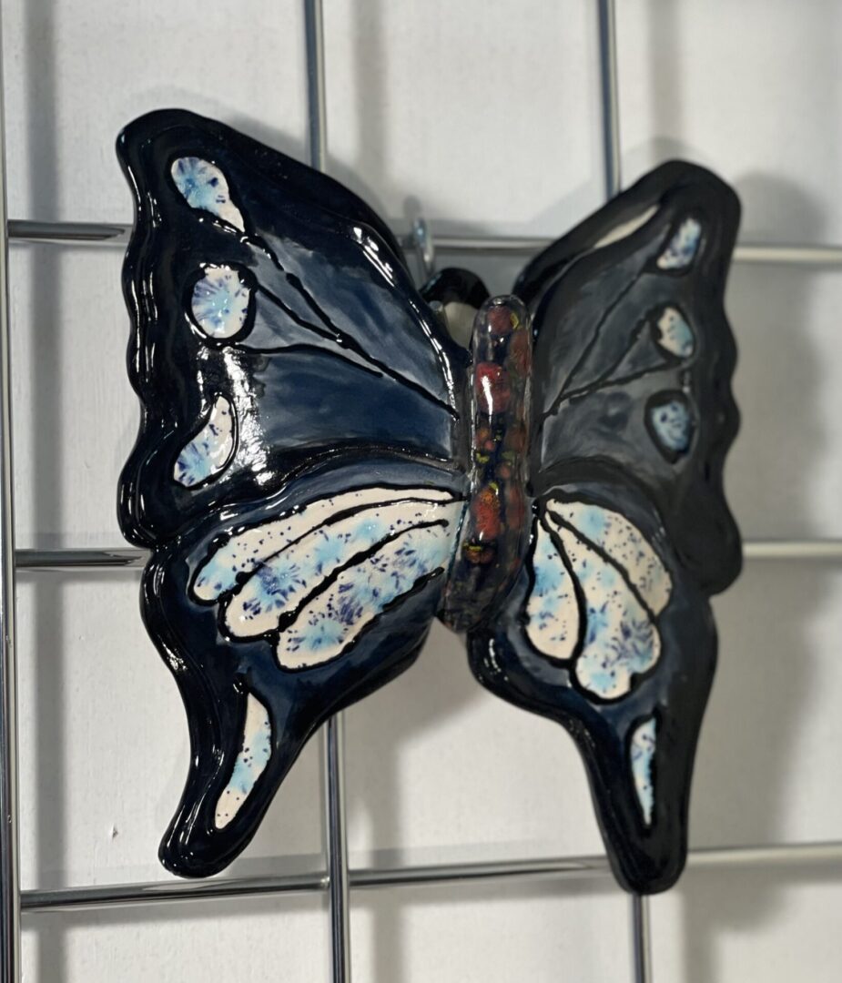 A blue and white ceramic butterfly hanging on a wire.
