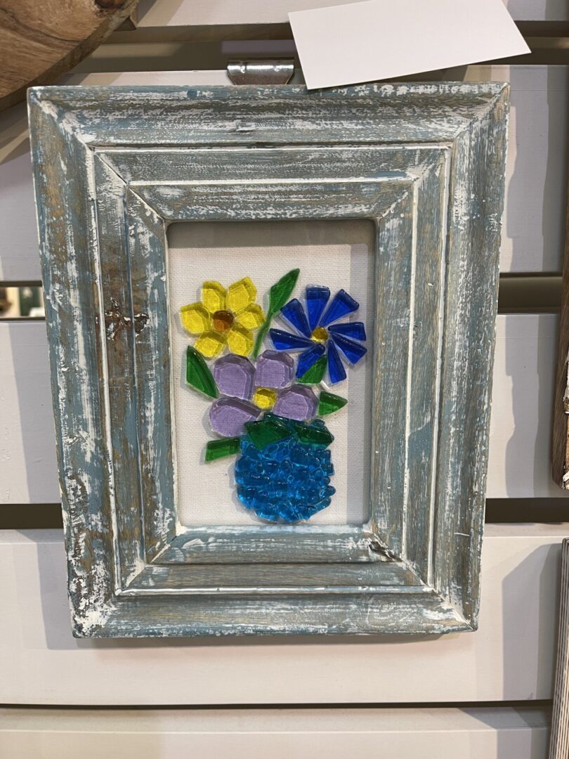 A framed glass vase with flowers in it.
