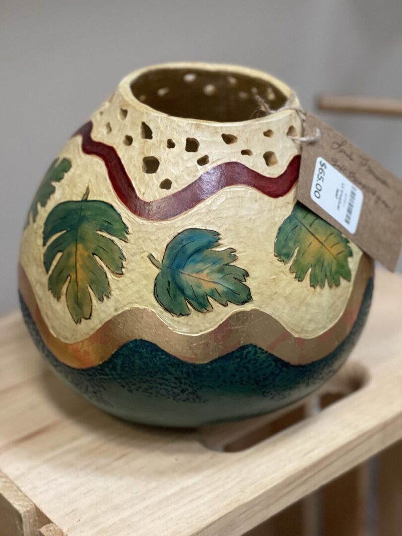 A vase with leaves painted on it is on display in a store.