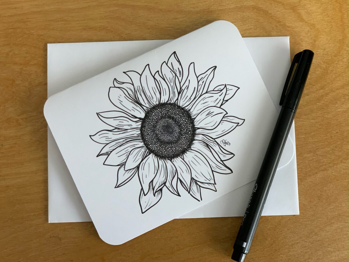 A note card with a sunflower drawing on it.
