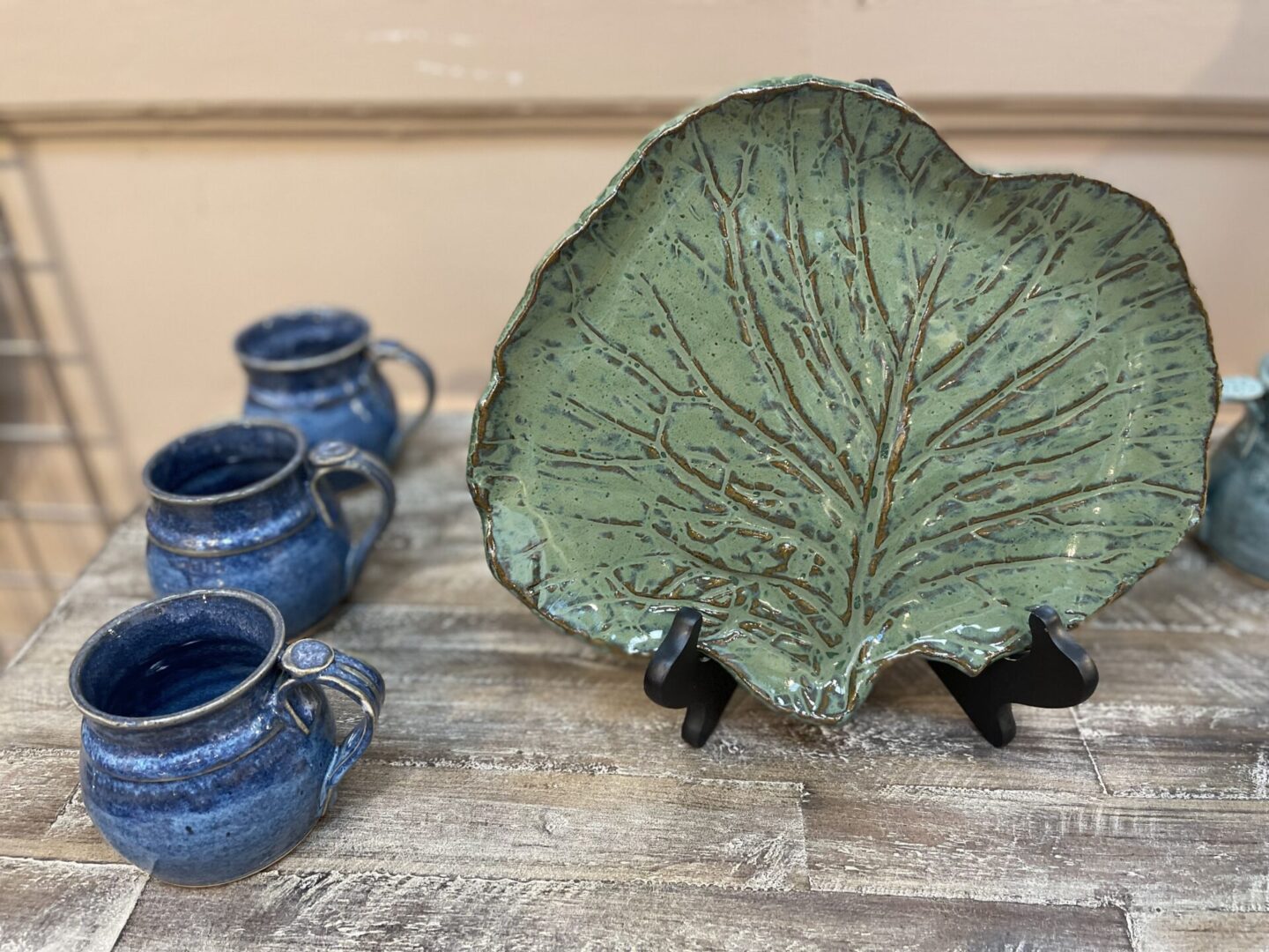 A set of mugs and a plate with a leaf on it.