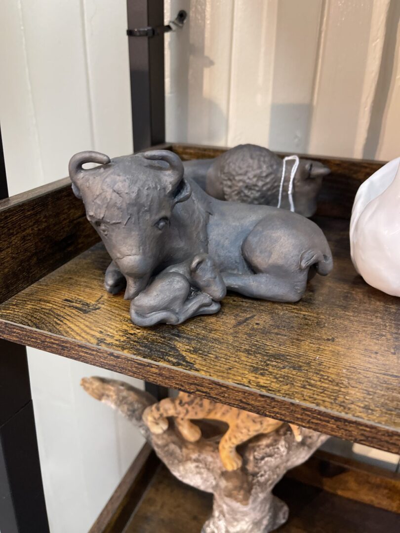 A shelf with a couple of cow figurines on it.