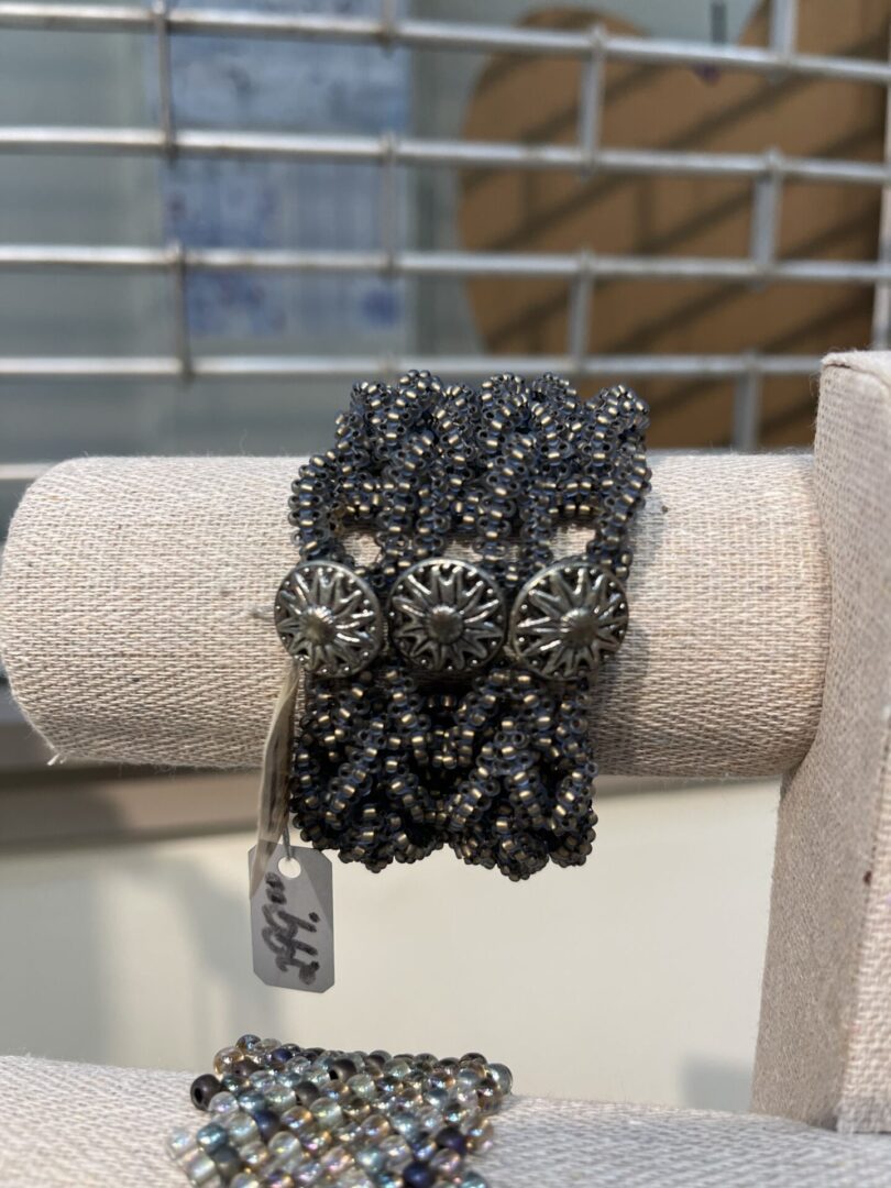 A pair of silver beaded bracelets sitting on a chair.