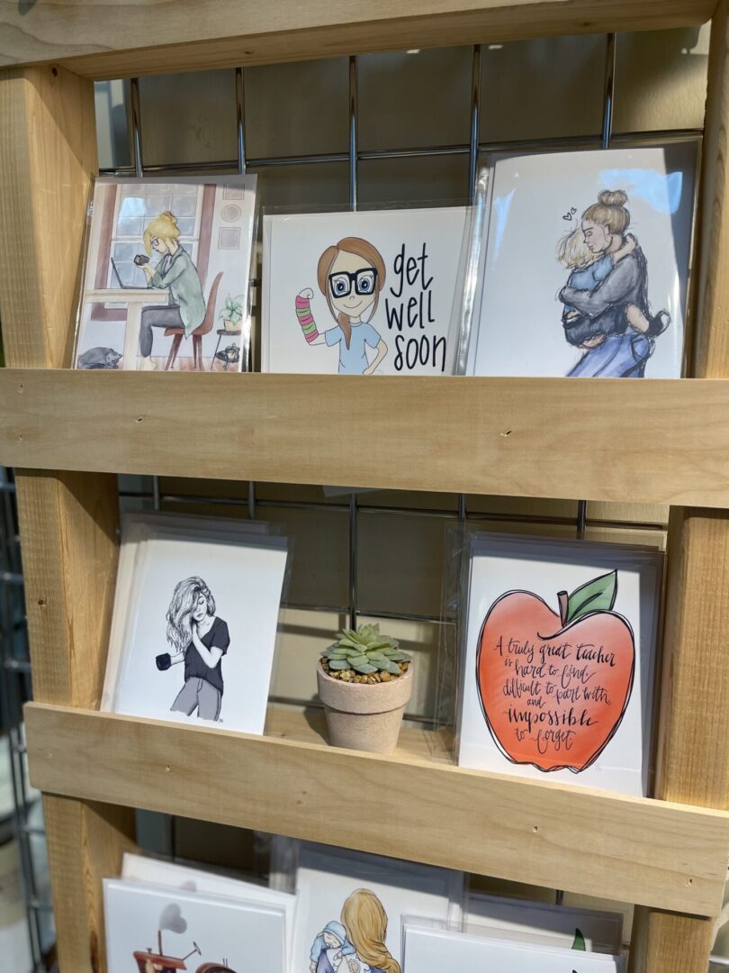 A display of greeting cards on a wooden shelf.