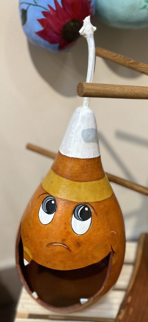 A pumpkin with a face on it is sitting on a shelf.