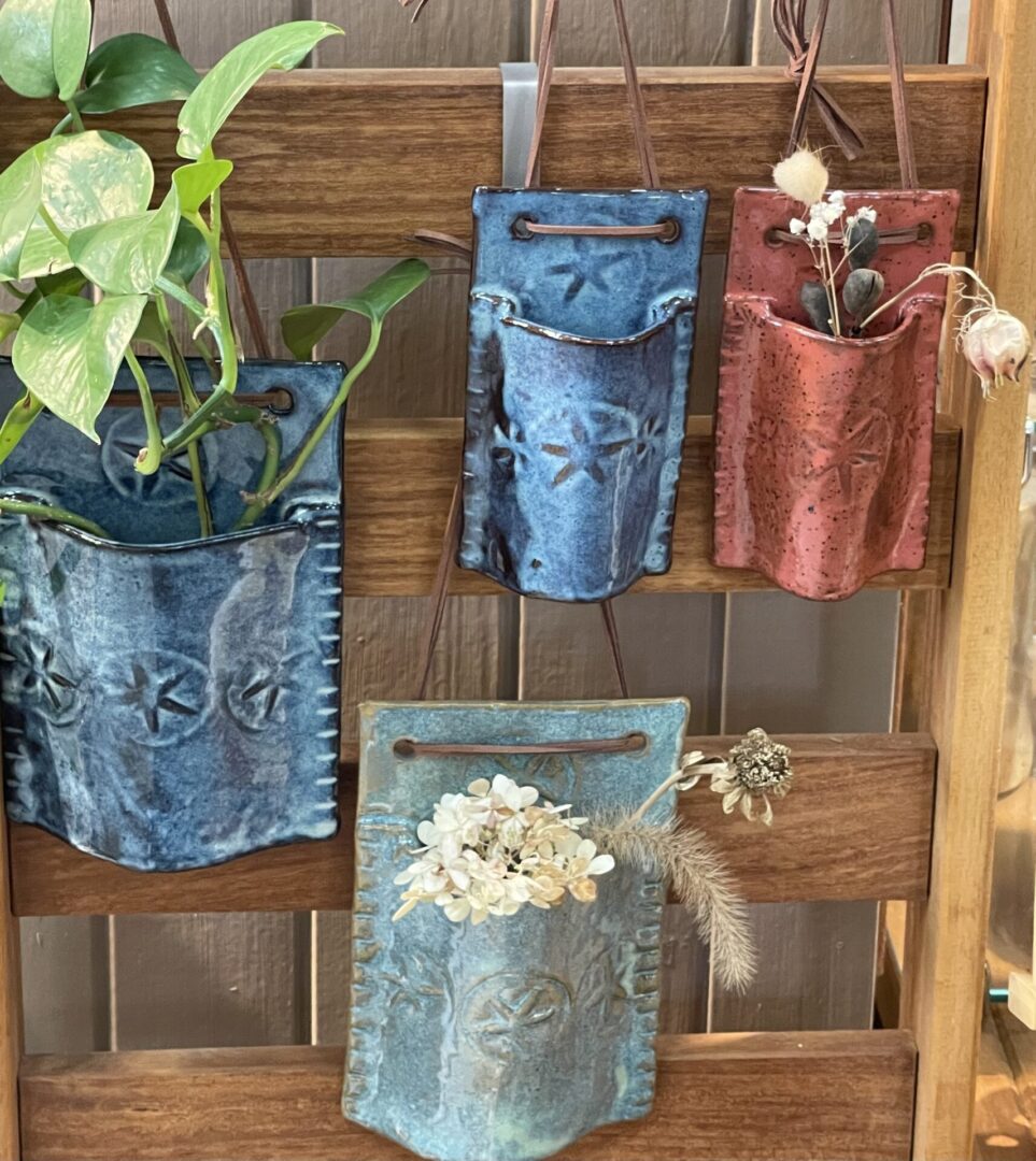 Four hanging ceramic planters on wood wall.