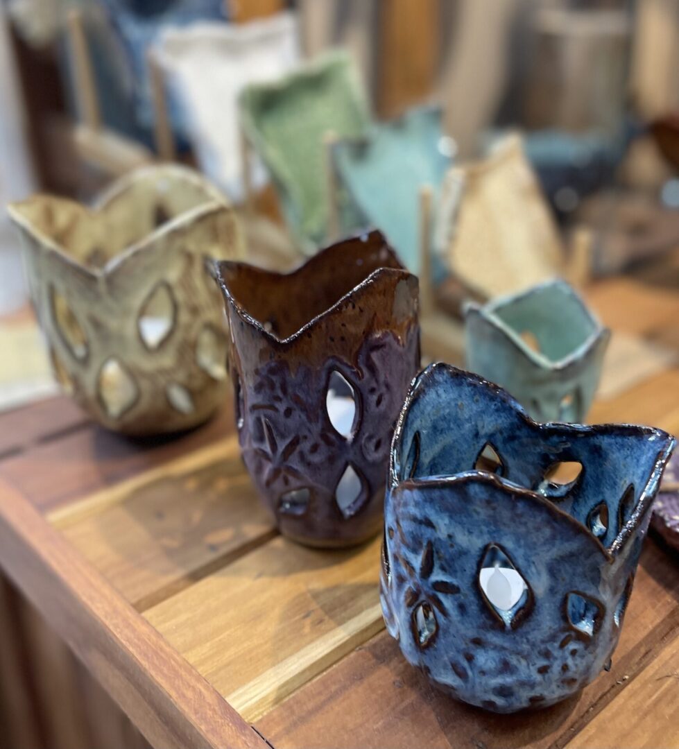 Four ceramic candle holders on wood table.