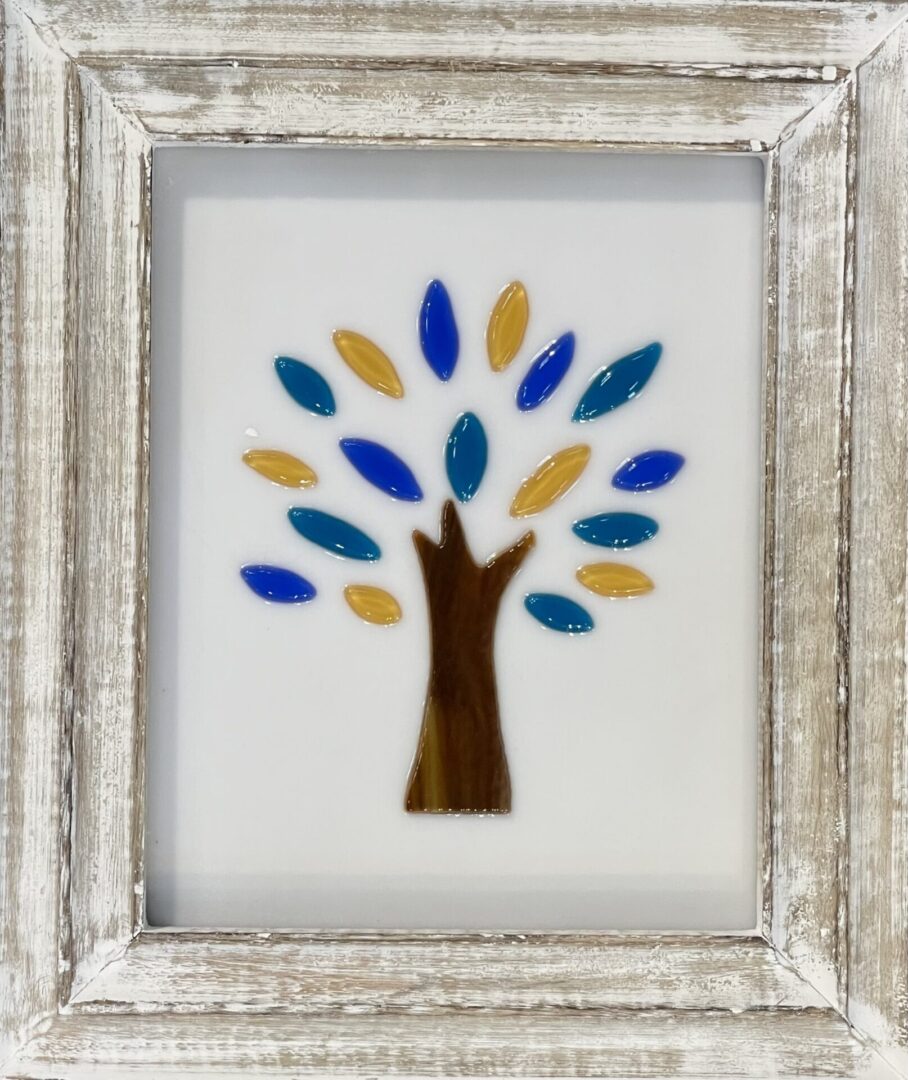 Framed stained glass tree with blue and yellow leaves.